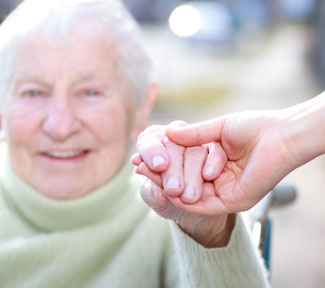A volunteer holding an elderly woman's hand